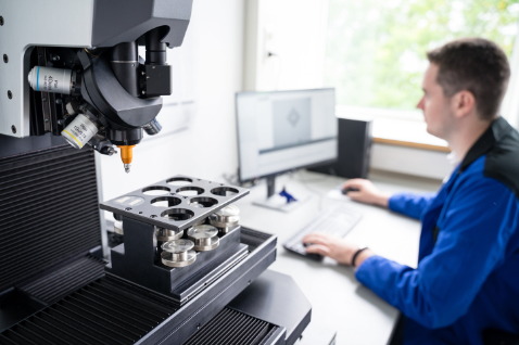An employee sits at a microscope