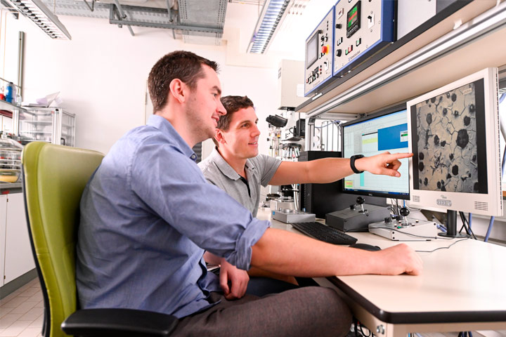 Zwei Wissenschaftler betrachten an einem Bildschirm ein Vergrößerung einer Materialaufnahme