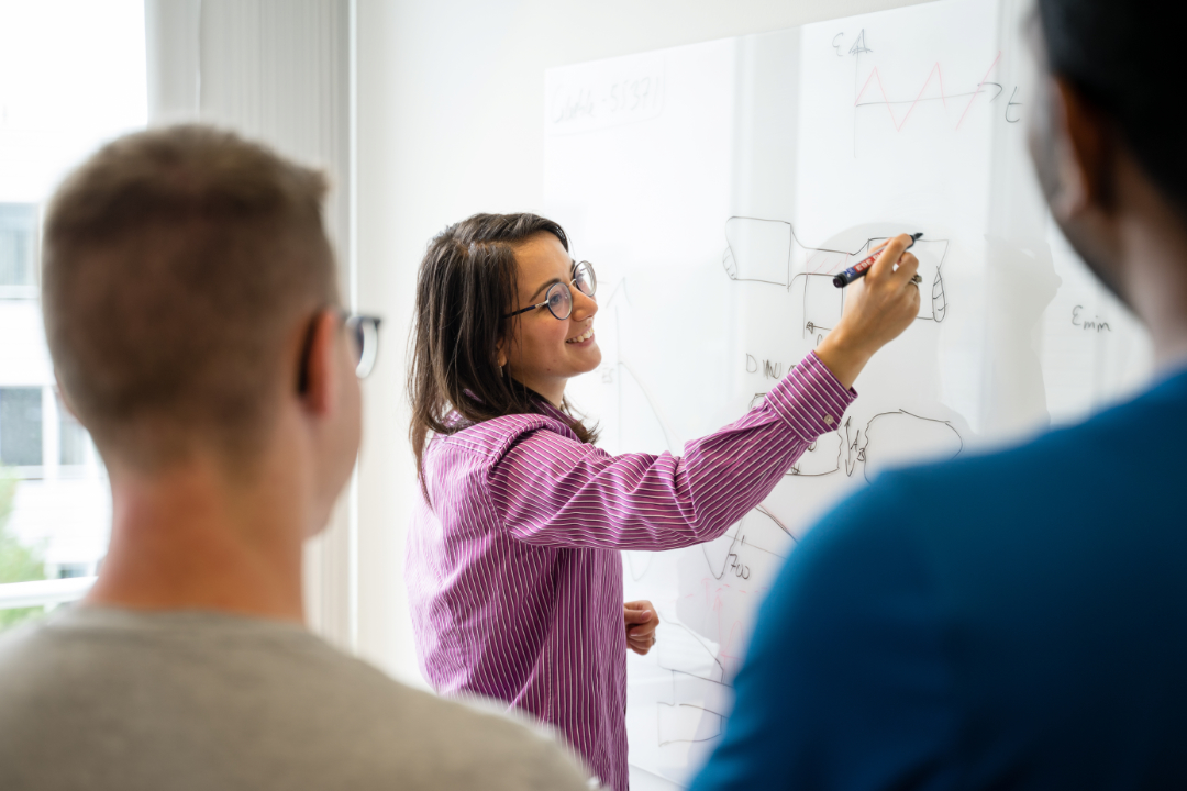 A woman draws a technical drawing on a whiteboard