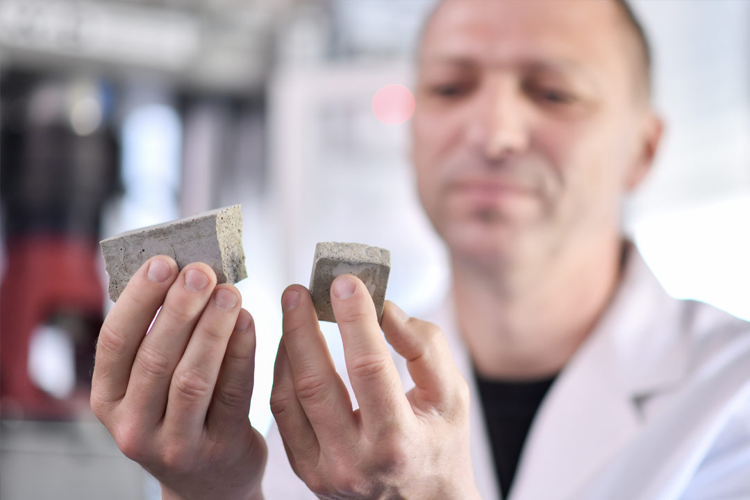 Ein Mitarbeiter hält zerbrochenen Beton in der Hand